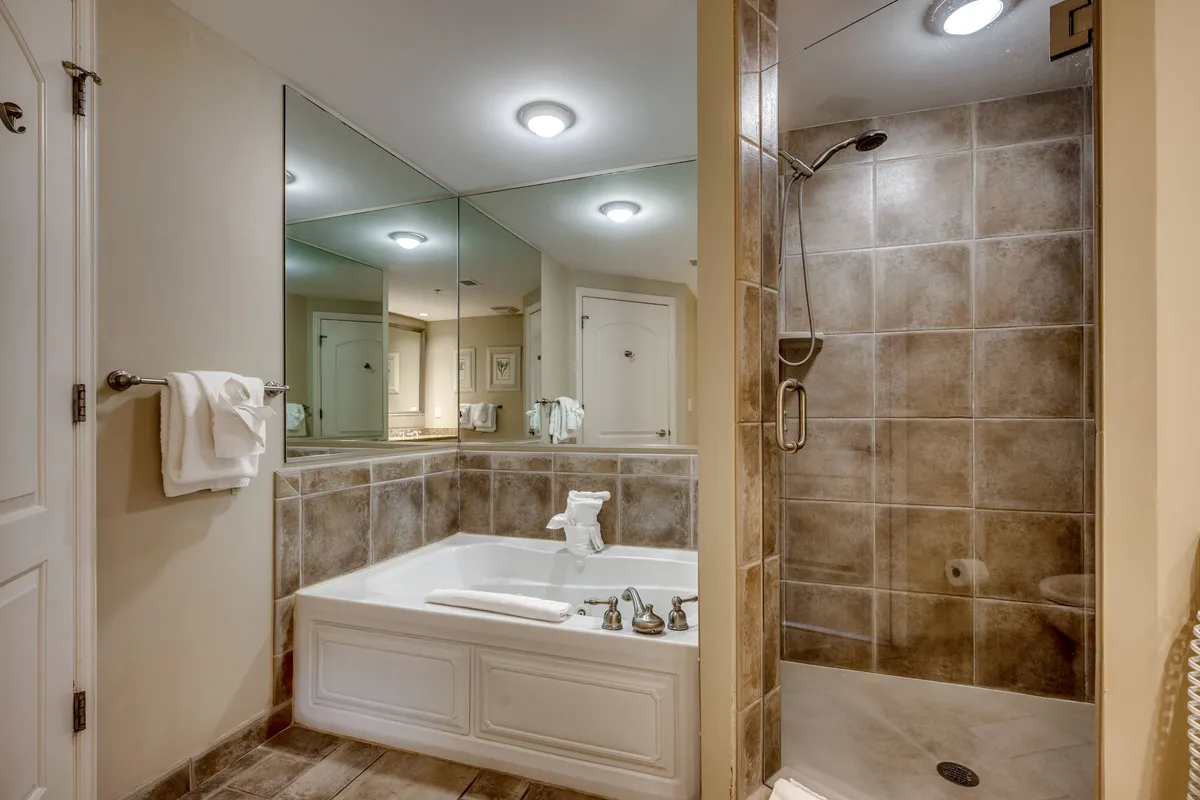 A tranquil ensuite bathroom with a bathtub, a separate shower area, mirrors, and a sleek vanity. The space feels luxurious and soothing, perfect for spa-like self-care moments.