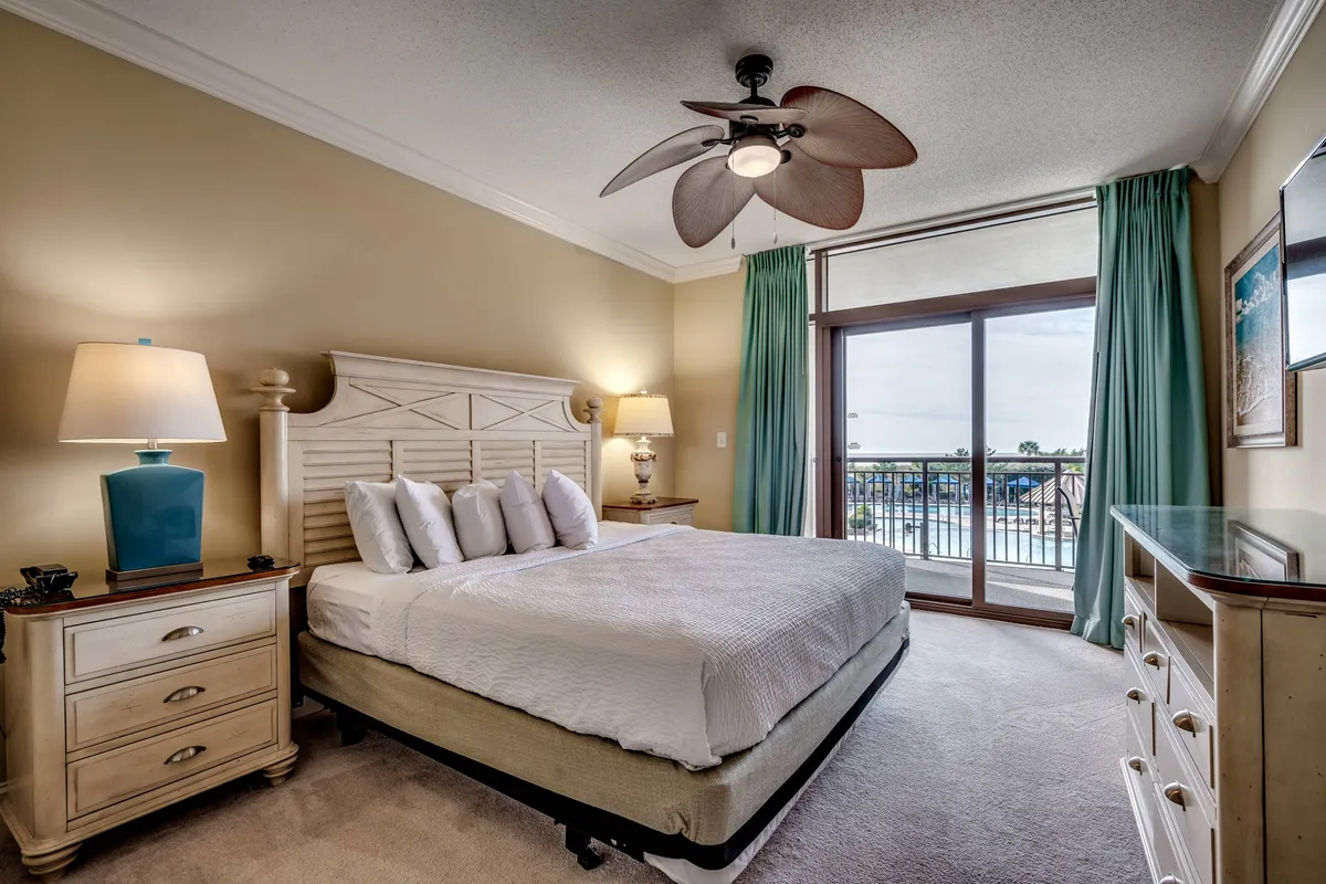 An interior view of a serene bedroom opening onto a private balcony, where morning sunlight streams in. The scene includes a cozy bed, a softly lit lamp, and a glimpse of the ocean beyond, evoking an intimate and peaceful start to the day for couples. The space is designed for comfort, privacy, and shared moments like enjoying coffee while taking in the sunrise.