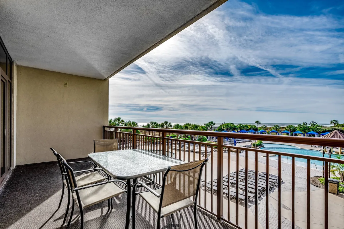 The private balcony is outfitted with a table and chairs, overlooking the pool area and open sky. The tranquil setting invites guests to step outside, relax, and enjoy beautiful views, seamlessly extending living space outdoors.